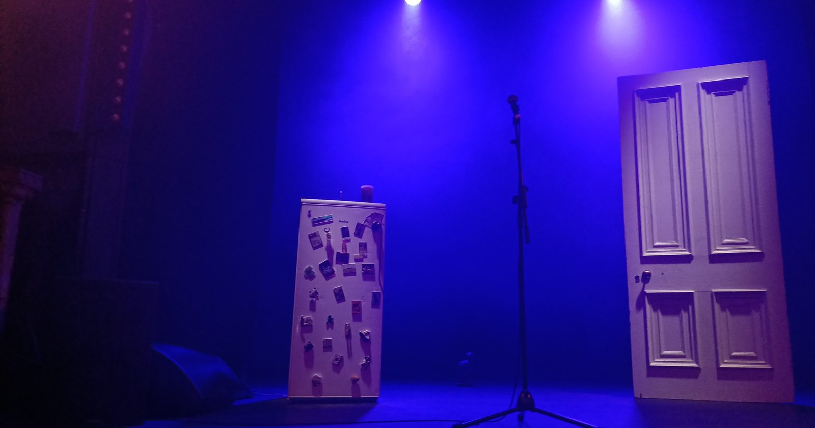 Reflektory oświetlające pustą scenę teatralną.